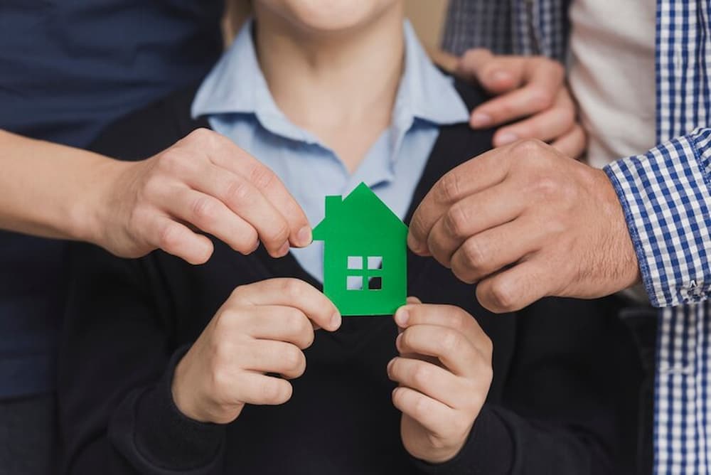 Padres e hijo sosteniendo figura de casa