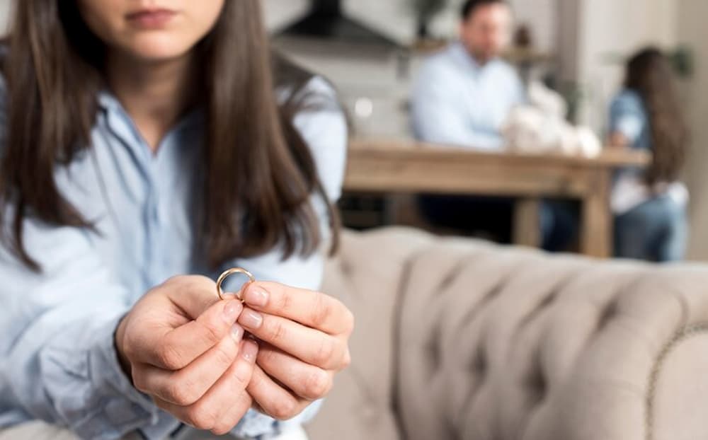 Mujer sosteniendo anillo con familia de fondo
